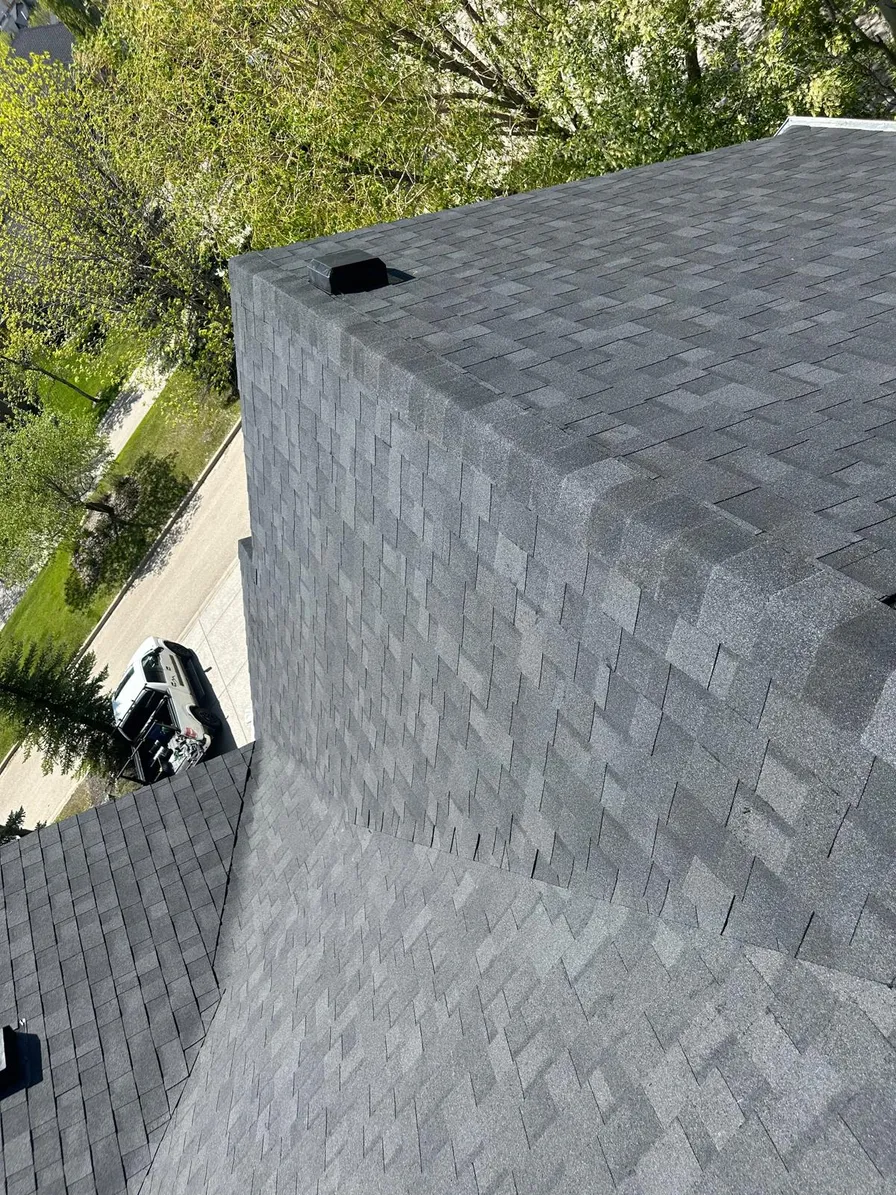 Inspecting a closed shingle valley for leaks from the ridge of a Calgary roof