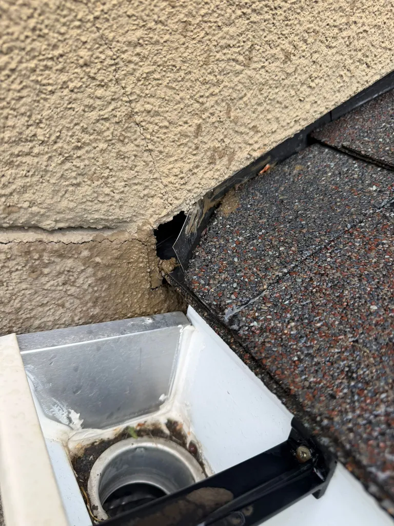 Close-up of a missing kickout flashing leaking behind stucco at the eave of a Tuscany home in northwest Calgary