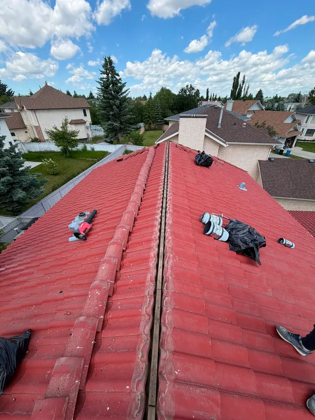 Ridge line of a red concrete tile roof in Calgary opened up for mortar renewal on the ridge caps