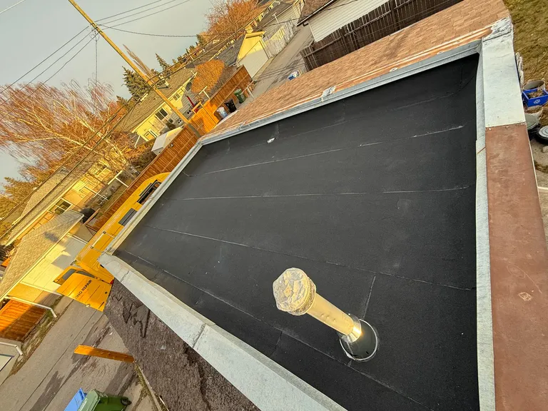 Removing old shingles and installing a new flat roof membrane on a Calgary home
