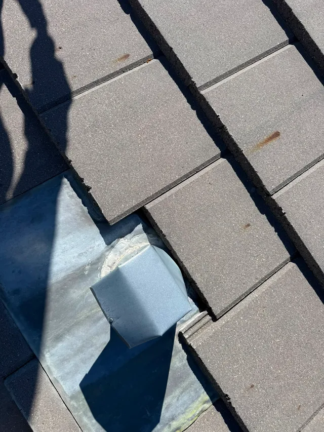 Metal vent flashing resealed with concrete roof tiles relaid in their original coursing